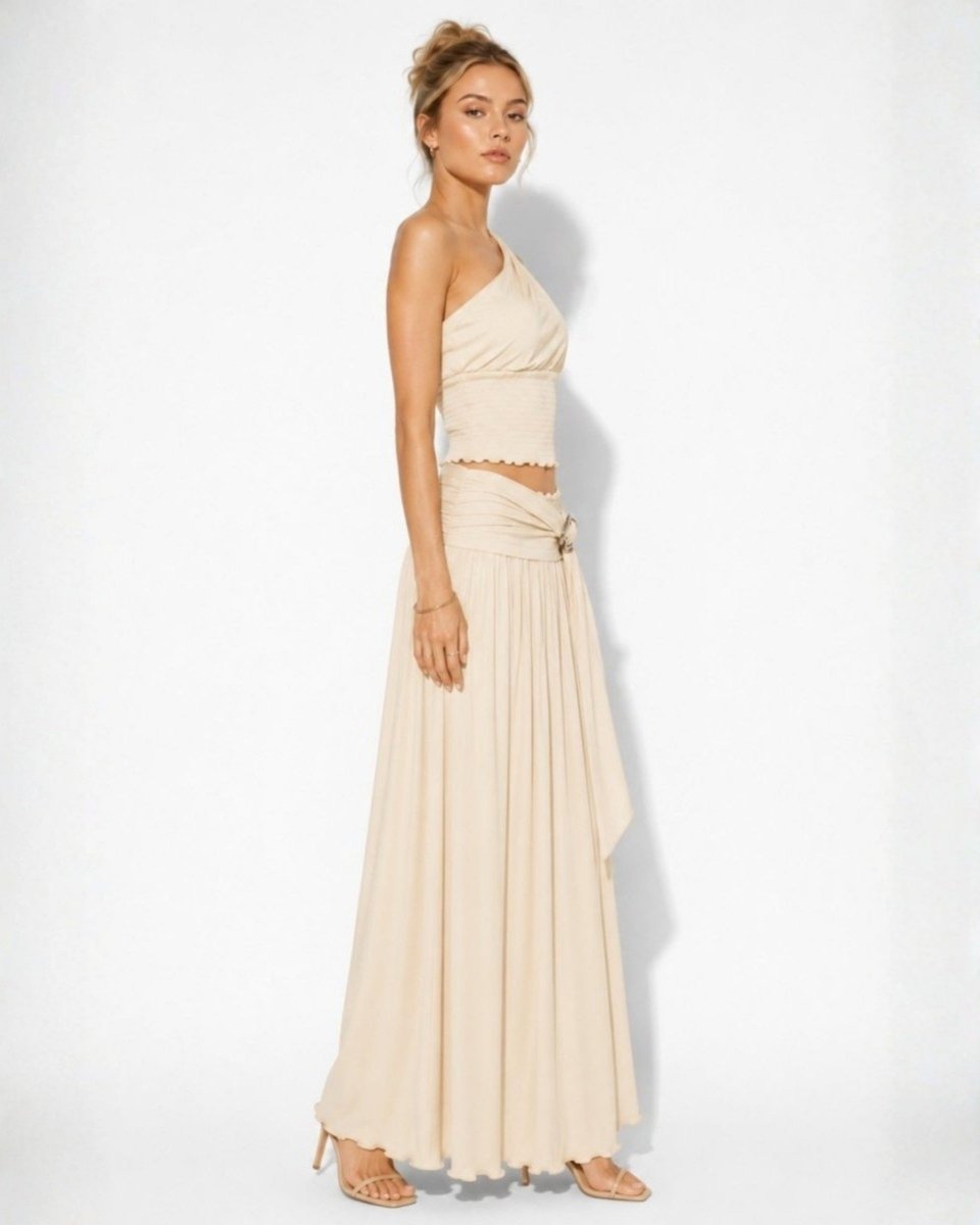 Side profile view of a beige smocked matching skirt set highlighting the custom metal belt hardware and flowing skirt drape.