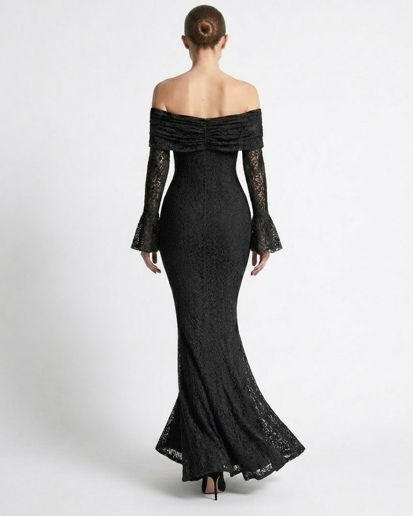 A woman viewed from the back wearing an off-the-shoulder black lace maxi gown with long flared sleeves and a fitted mermaid silhouette, photographed against a plain light gray studio background.