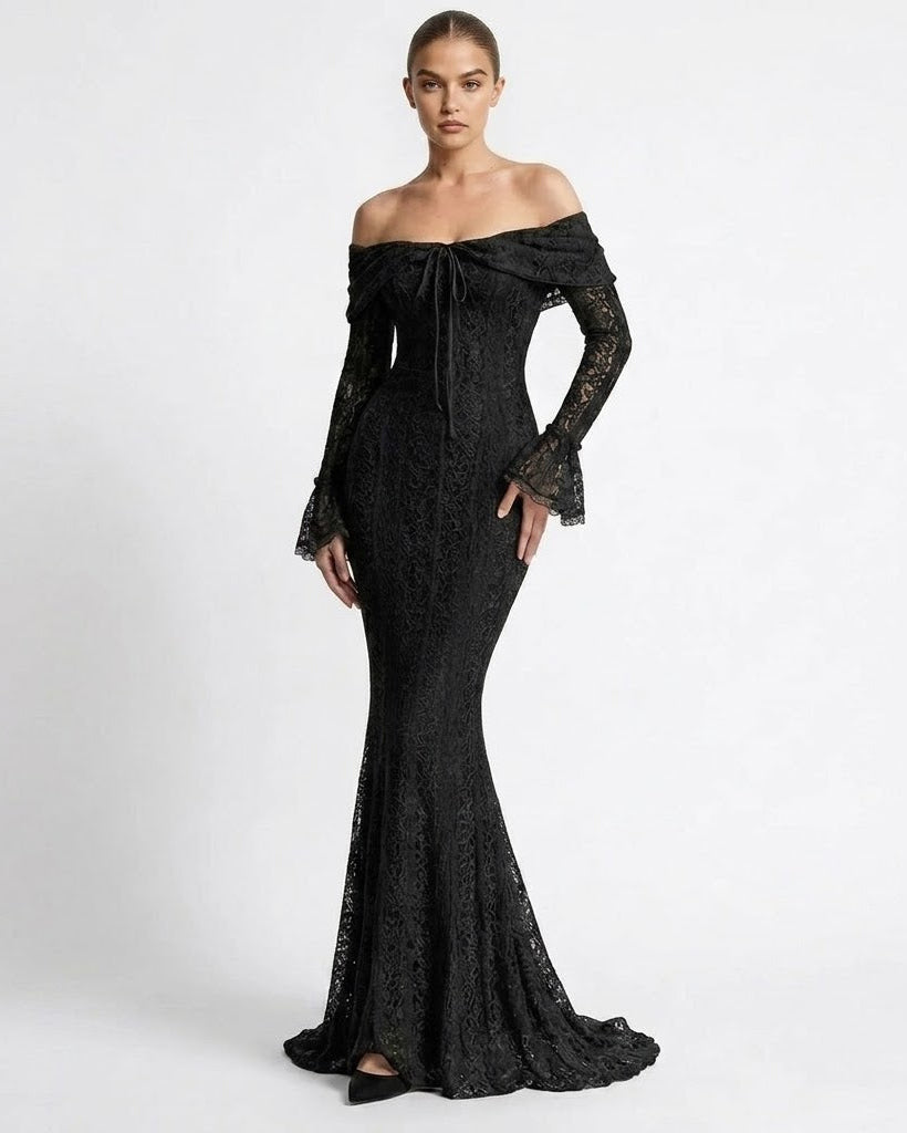 A woman modeling an off-the-shoulder black lace gown with long flared sleeves and a fitted mermaid silhouette, photographed against a clean light gray studio background.