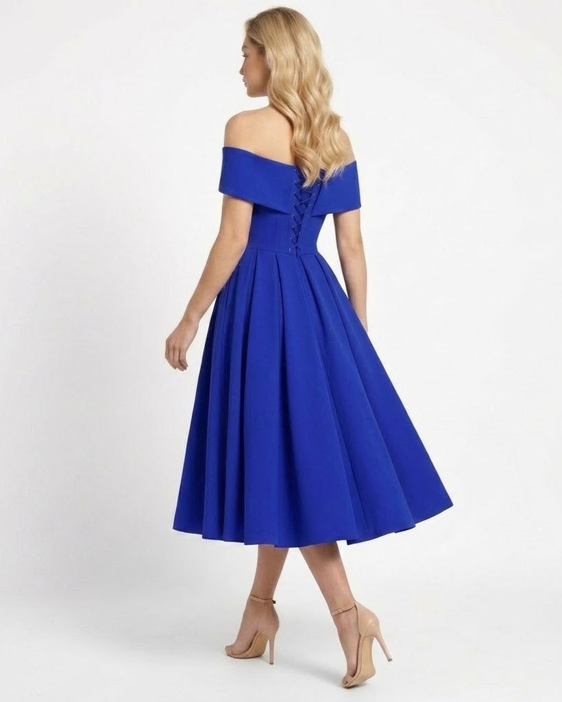 A woman modeling an off-the-shoulder royal blue midi dress with a flared skirt and lace-up back, shown from the back against a plain white studio background.
