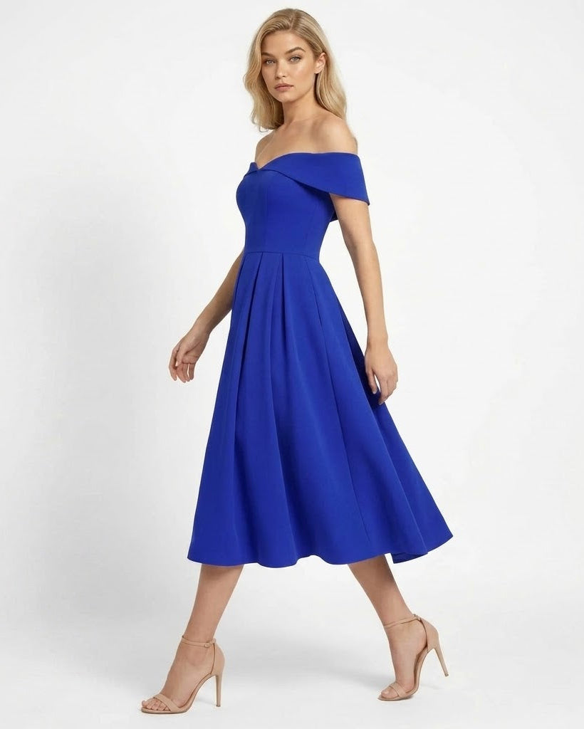 A woman modeling a bright royal blue off-the-shoulder midi dress with a flared skirt, paired with nude high-heeled sandals, against a clean white studio background.