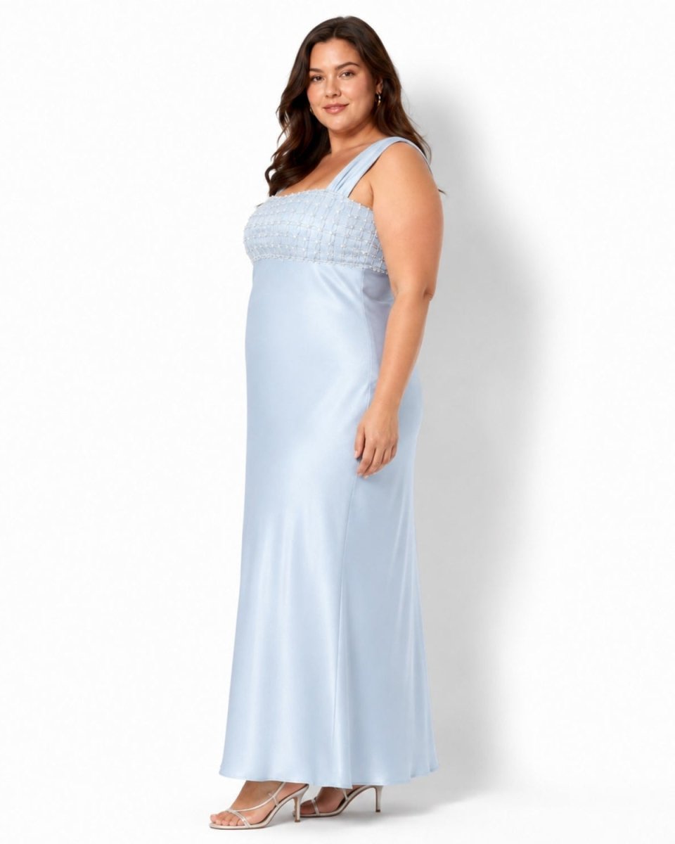 Side profile of a plus size model in the Ondara powder blue satin maxi dress, showing the intricate pearl beaded bodice and elegant A-line floor-length silhouette.