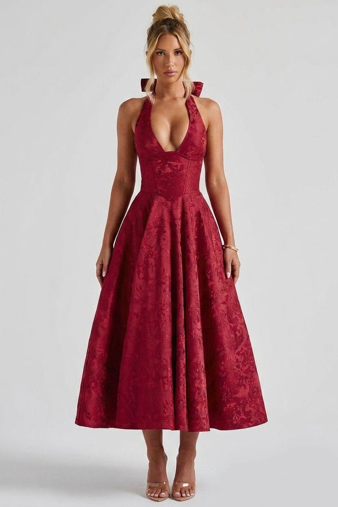 Front view of the ruby red floral jacquard halter corset midi dress by Ondara, modeled with clear heels for a wedding guest look.