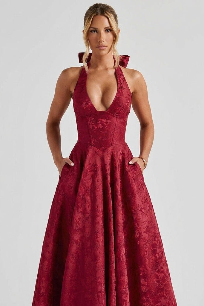 Lifestyle shot of the red halter cocktail dress demonstrating the functional, deep side pockets hidden in the A-line skirt.