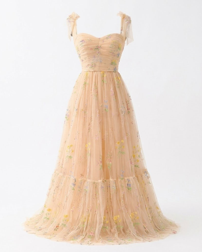 A peach-colored A-line evening gown with a sweetheart neckline, sheer flutter shoulder straps, and delicate multicolor floral embroidery, displayed on a clean white background.