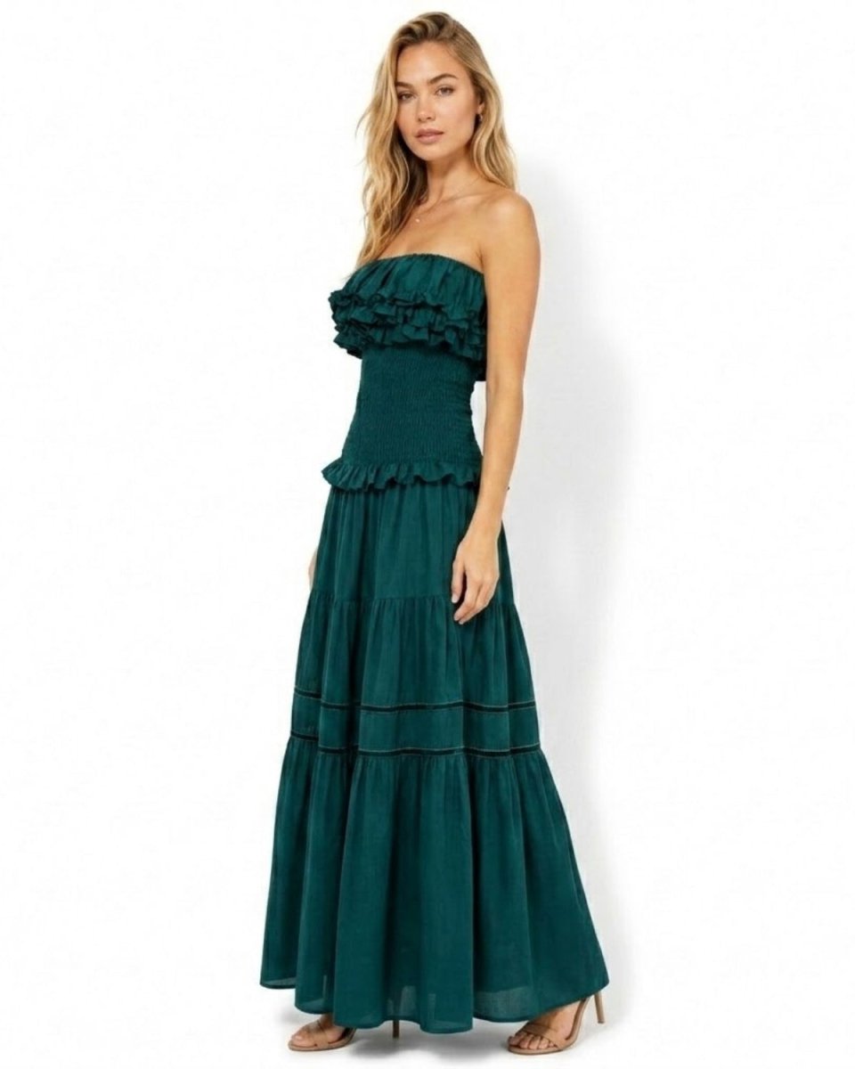 Side profile of the dark green strapless tiered maxi dress highlighting the secure smocked fit and flowing A-line skirt silhouette.