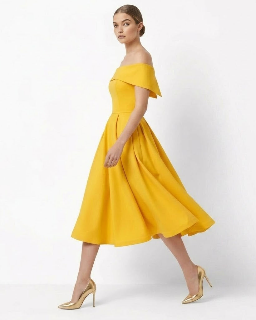 A woman models a bright yellow off-the-shoulder midi dress with a flared skirt, paired with metallic gold high heels, against a clean white studio background.