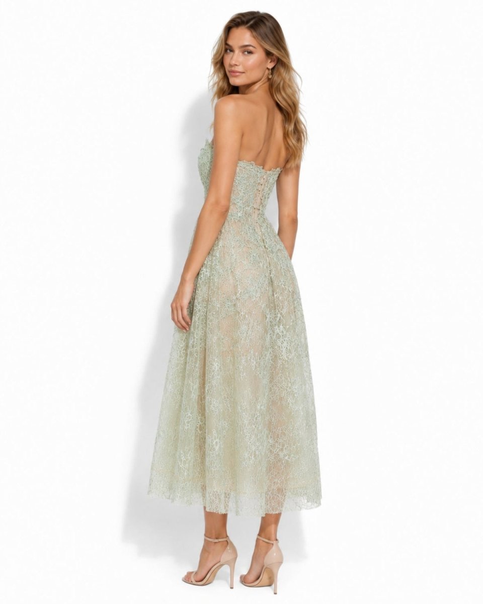 Side angle of a model showing the flattering fit and lace overlay of the green strapless lace midi dress.