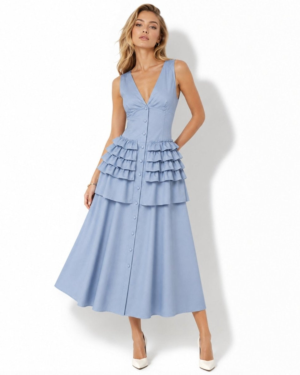 A woman modeling a sleeveless light blue midi dress with a deep V-neckline, button-front bodice, and tiered ruffle detailing at the waist, photographed against a plain white studio background.