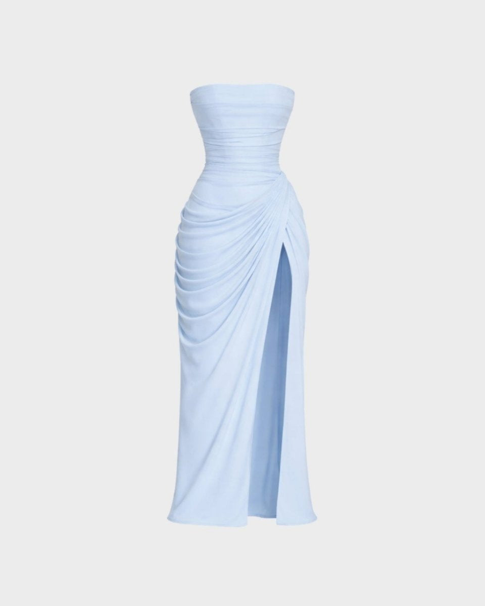 A light blue strapless maxi dress with a ruched bodice, draped skirt details, and a high front slit, shown against a plain light gray background.