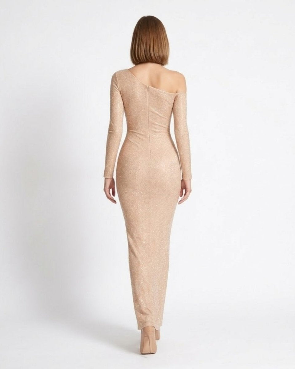 A woman viewed from the back wearing a fitted, one-shoulder nude-beige long-sleeve dress against a plain light gray studio background.