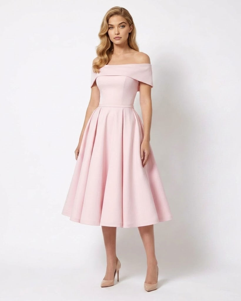 A woman models a light pink off-the-shoulder midi dress with a structured bodice and a full, flared skirt, paired with nude high heels against a plain white studio background.