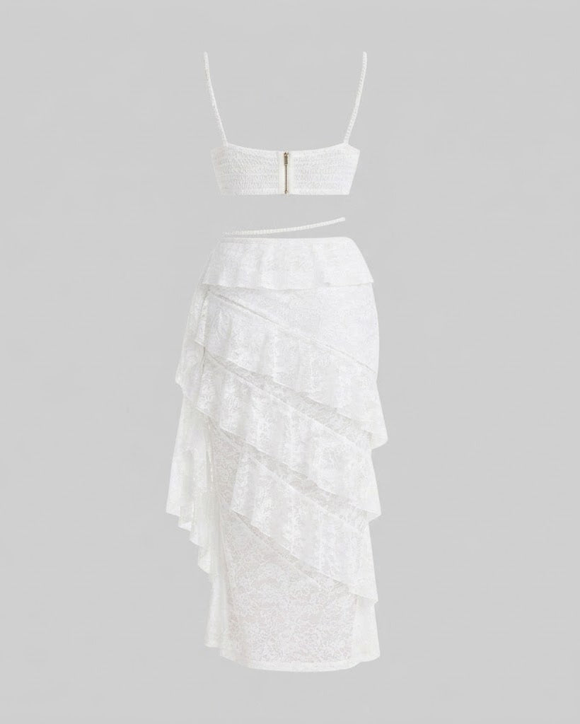 White two-piece set featuring a strapless lace crop top with a central gold zipper and a matching tiered ruffle skirt, displayed on a neutral gray background.