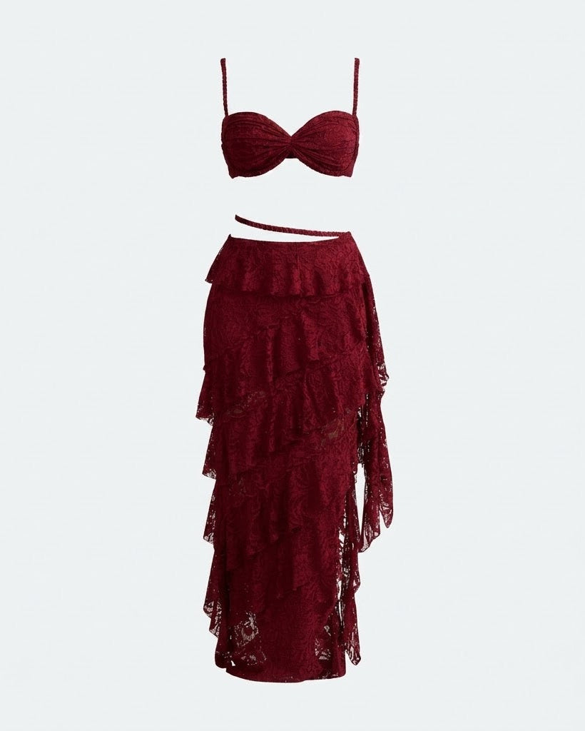 A two-piece women's outfit in deep burgundy lace, featuring a structured bralette top with thin shoulder straps and a matching tiered ruffle maxi skirt with an asymmetrical hem.