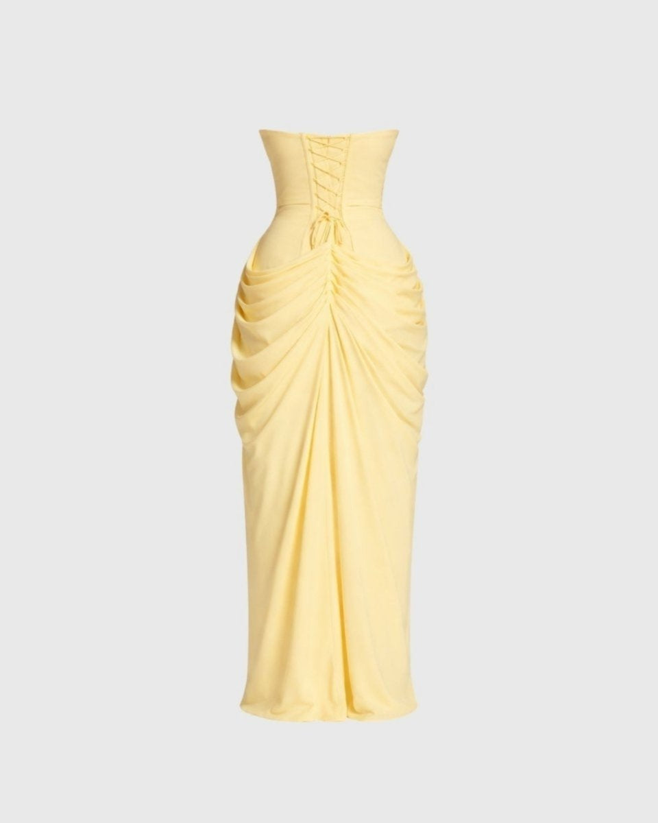 A pale yellow strapless maxi dress with a corset-style waist and gathered ruching, shown on a light gray background.
