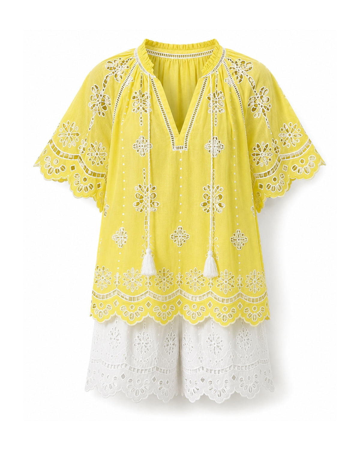 A bright yellow short-sleeve tunic top with intricate white floral eyelet embroidery, tassel ties, and a layered white lace skirt, shown against a plain white background.