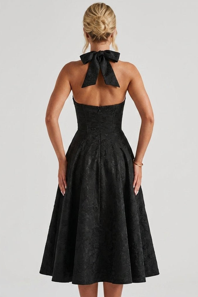 Back view of the black open back cocktail dress, showcasing the statement halter bow tie and corset bodice.