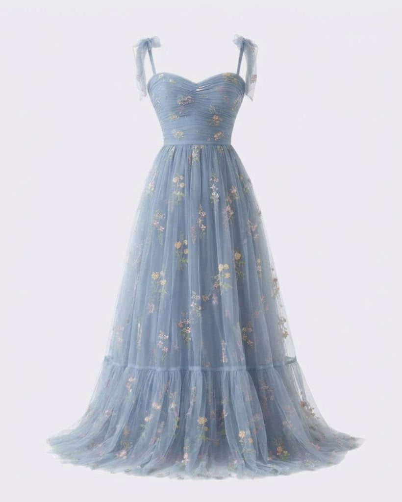 A light blue tulle evening gown with a sweetheart neckline, delicate floral embroidery, and tie straps on the shoulders, shown against a plain light gray background.