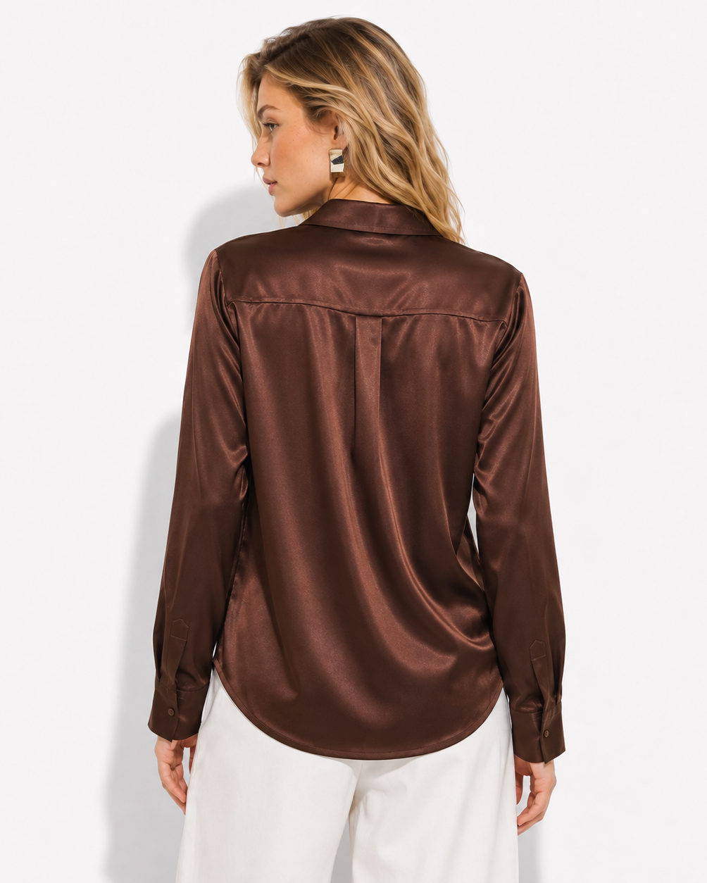 A woman shown from the back wearing a brown satin button-down shirt and white pants, photographed against a clean white studio background.