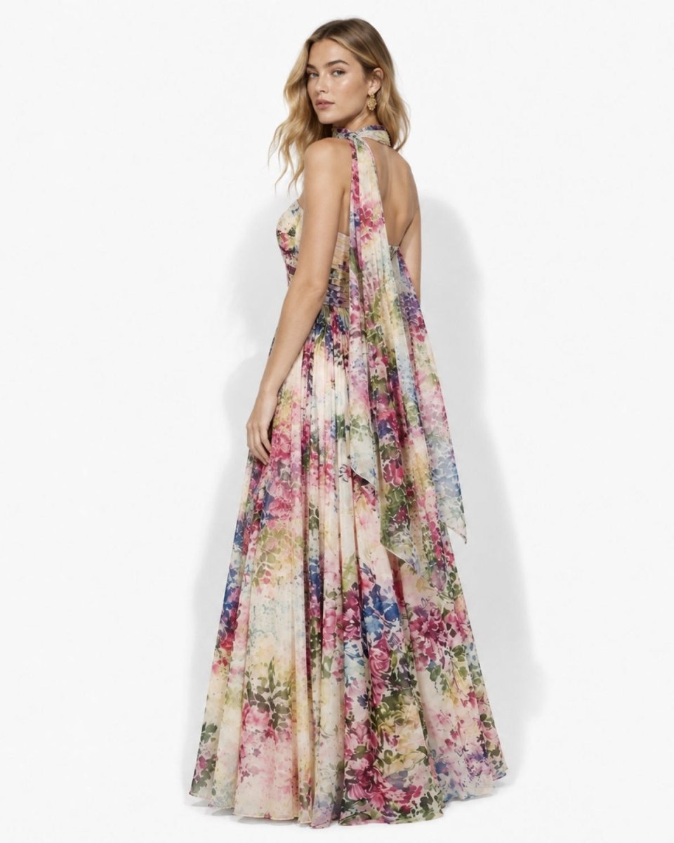 Back angle view of a strapless floral chiffon evening dress, showcasing the dramatic draped scarf detail and elegant sweeping hemline.