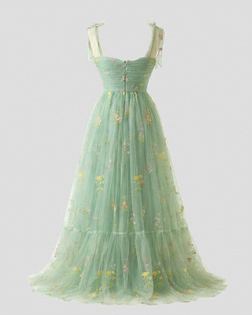 A light mint green tulle maxi dress with a sweetheart neckline, corset-style bodice, and delicate floral embroidery, shown against a solid light gray background.