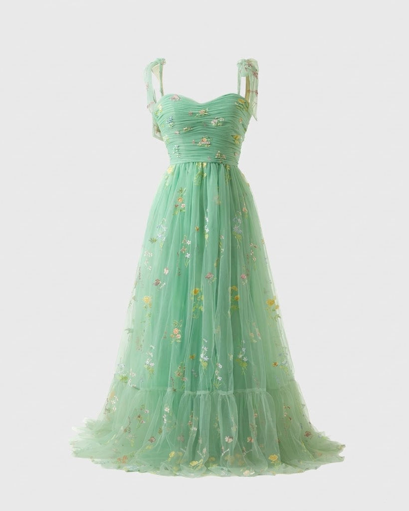 A mint green sleeveless tulle gown with a sweetheart neckline, ruched bodice, and delicate floral embroidery, shown against a light gray background.