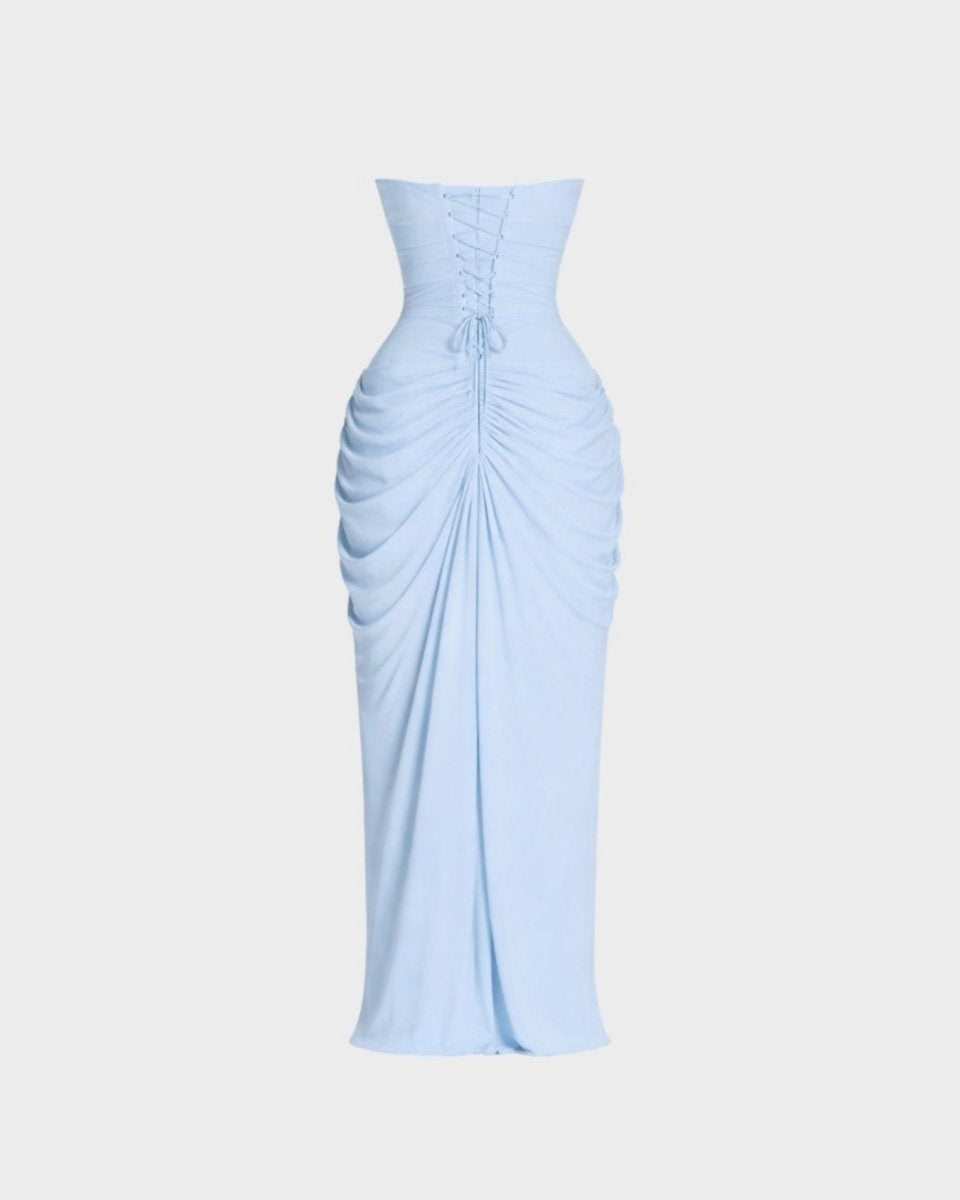 A light blue strapless maxi dress with a corset-style waist, front lace-up detailing, and dramatic gathered draping on the skirt, shown against a plain light gray background.