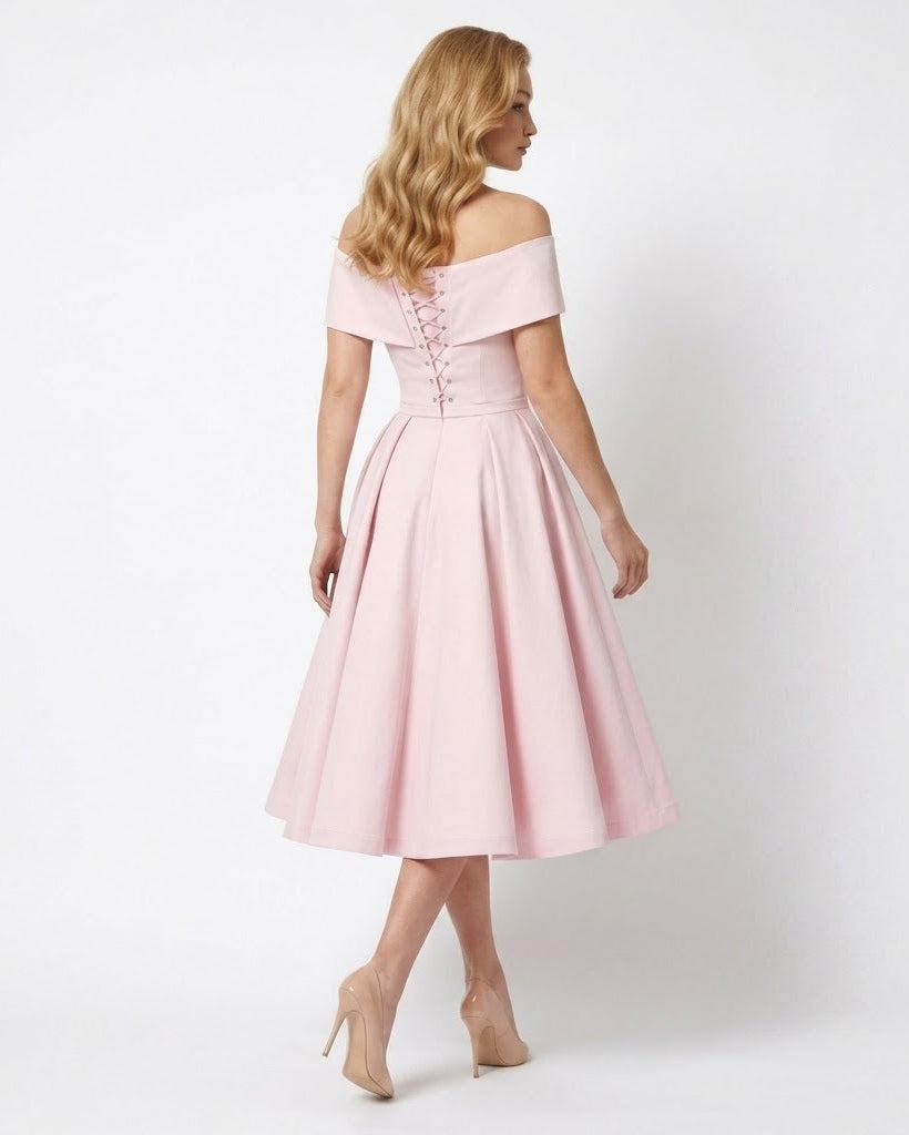A woman modeling an off-the-shoulder pink midi dress with a lace-up back, shown from behind against a plain white studio background.