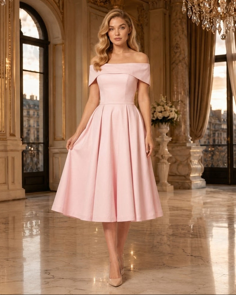 A woman models an off-the-shoulder pink midi dress in a luxurious, ornate ballroom with gold columns and chandeliers.