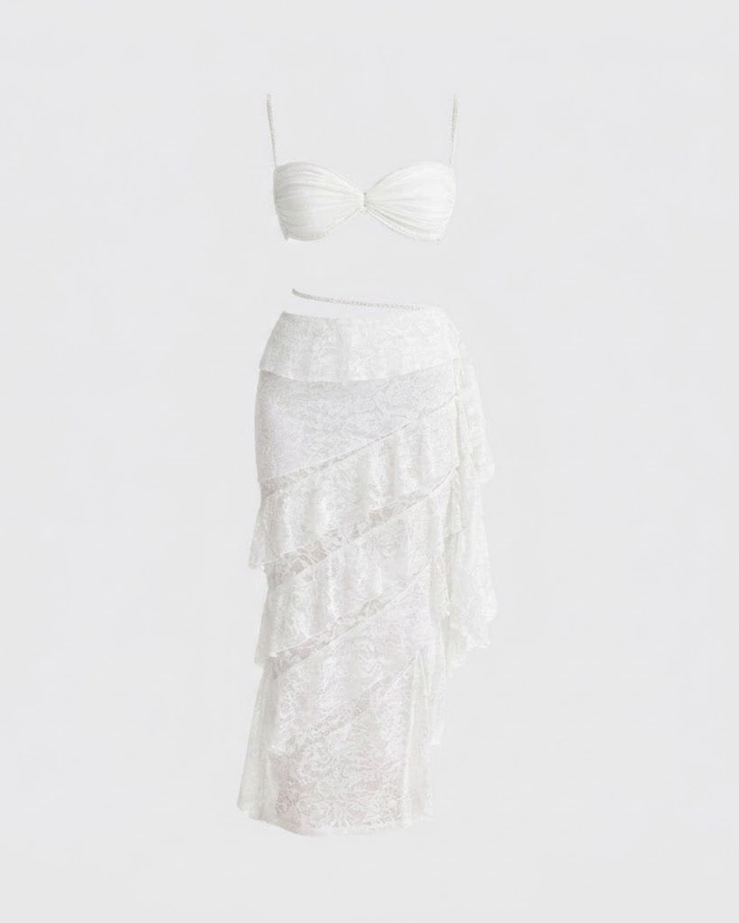 White two-piece swimwear set featuring a strapless bandeau-style top with a twisted neckline and a tiered ruffle skirt, displayed on a solid white background.