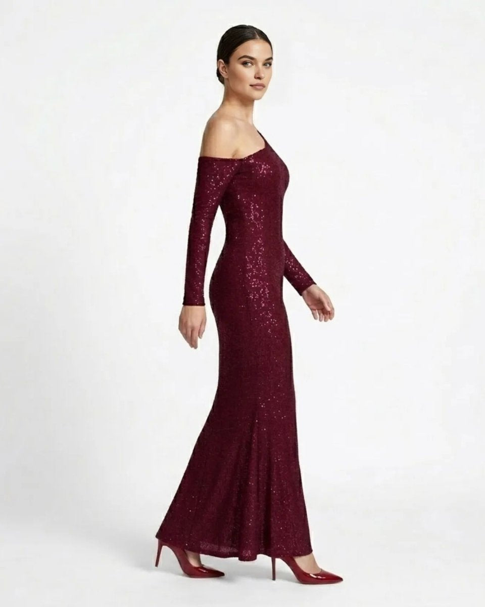 A woman modeling a long-sleeve off-the-shoulder floor-length gown covered in sparkling burgundy sequins, paired with matching burgundy high heels, against a plain white studio background.